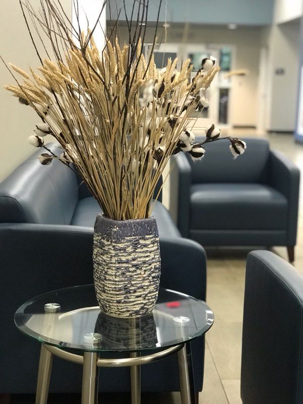 A vase filled with dried grass sits elegantly on a wooden table